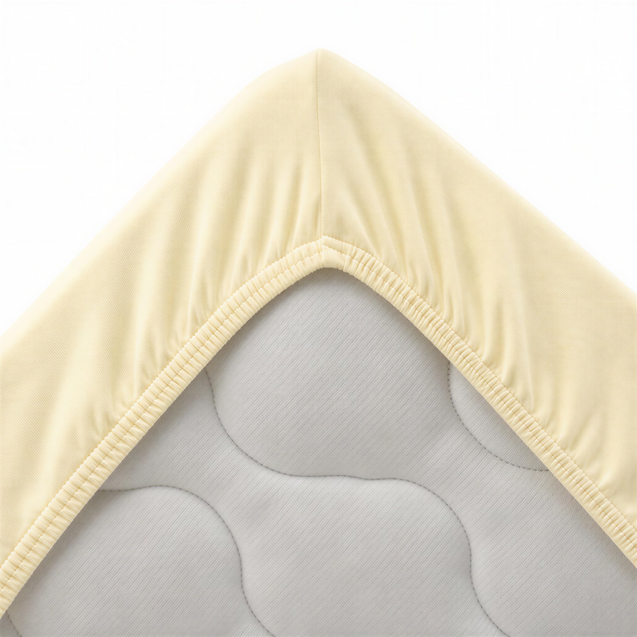 Vanillefarbenes Spannbettlaken aufgezogen auf einem Bett im Schlafzimmer
